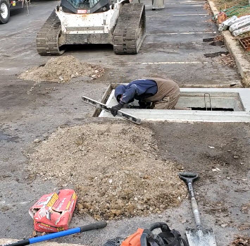 Level sewer inlet with surrounding asphalt parking lot